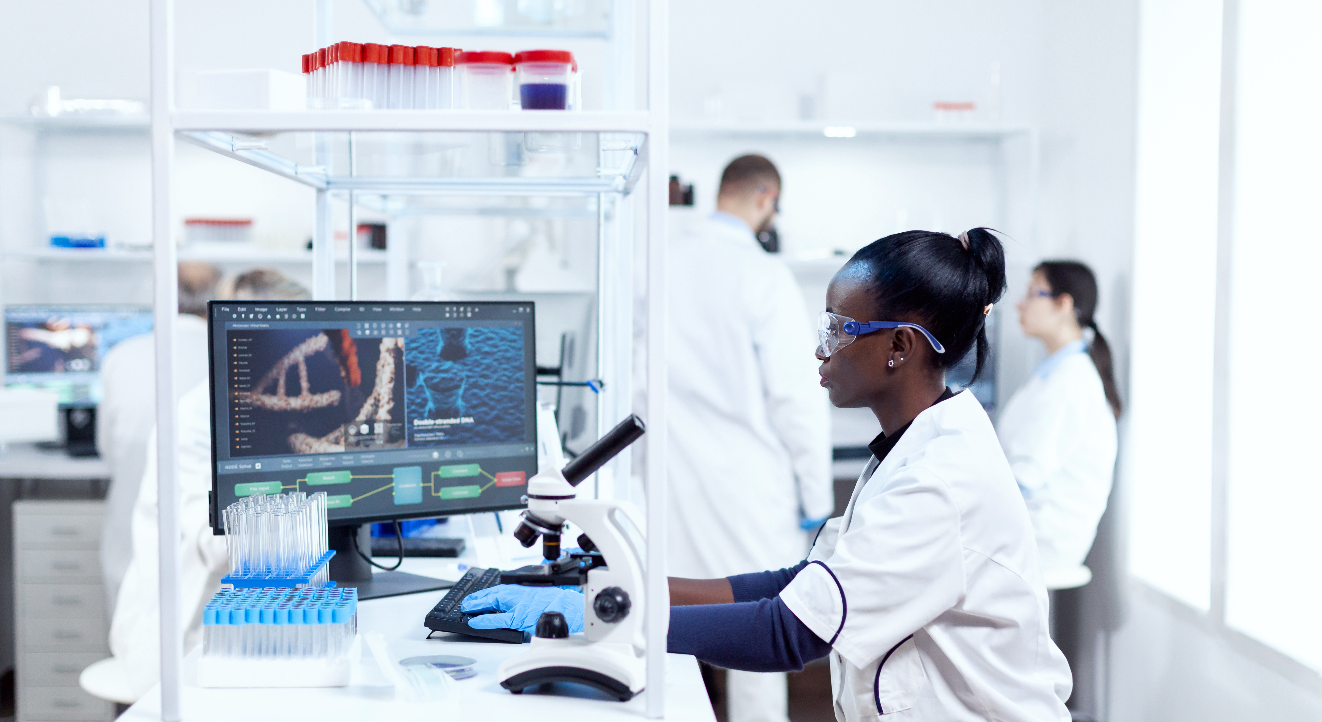 Three researchers in lab coats working in a lab.