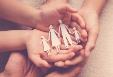 three pairs of hands with paper cut out of a family